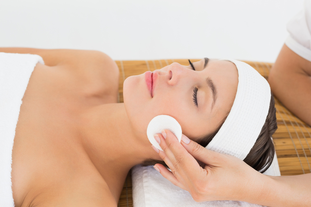 Hand cleaning womans face with cotton swabs at spa center